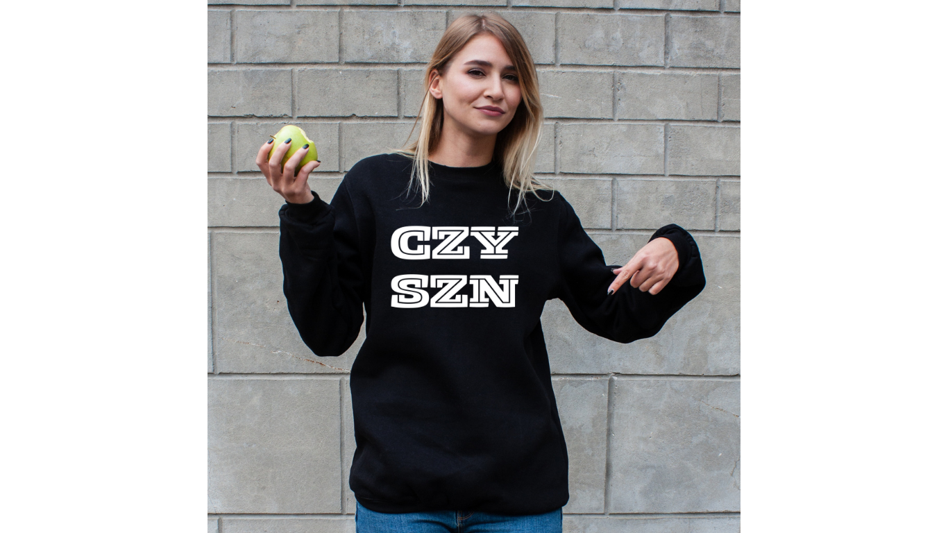 Woman wearing a cozy sweatshirt that says czy szn standing for cozy season sweatshirt